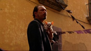 Movie still from “Once Upon a Time in Mexico” (2003), directed by Robert Rodriguez – A man holding a small dog in his arms; Medium shot, Low angle