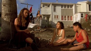 Movie still from “Once Were Warriors” (1994), directed by Lee Tamahori – A woman sitting on the ground next to two other women; Medium shot, Over the shoulder angle