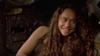 Movie still from “Once Were Warriors” (1994), directed by Lee Tamahori – A woman with curly hair smiling for the camera; Close Up shot, Over the shoulder angle