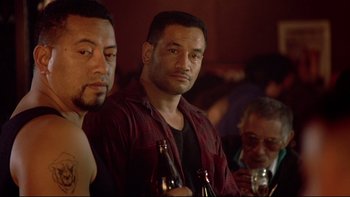 Movie still from “Once Were Warriors” (1994), directed by Lee Tamahori – A group of men sitting at a table with bottles of beer; Close Up shot, Over the shoulder angle
