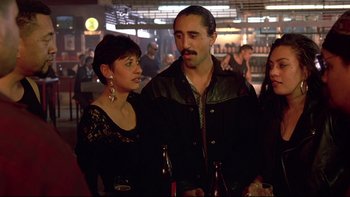 Movie still from “Once Were Warriors” (1994), directed by Lee Tamahori – A man and a woman standing next to each other holding beers; Medium shot, Over the shoulder angle