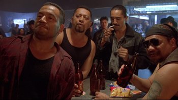 Movie still from “Once Were Warriors” (1994), directed by Lee Tamahori – A group of men sitting at a bar drinking beer; Medium shot, Over the shoulder angle