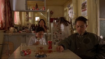 Movie still from “Once Were Warriors” (1994), directed by Lee Tamahori – A man sitting at a table with two children; Medium shot, High angle