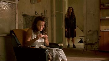 Movie still from “Once Were Warriors” (1994), directed by Lee Tamahori – A woman sitting on a chair in front of a fire place; Medium shot, Low angle