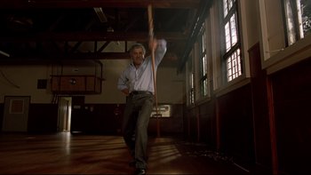 Movie still from “Once Were Warriors” (1994), directed by Lee Tamahori – A man holding a wooden stick in a room; Medium shot, Low angle