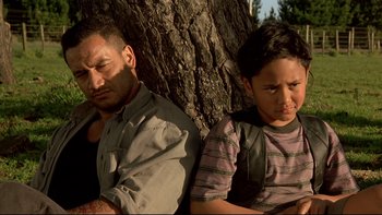 Movie still from “Once Were Warriors” (1994), directed by Lee Tamahori – A man and a girl sitting next to a tree; Medium shot, Over the shoulder angle