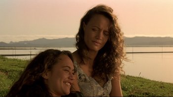 Movie still from “Once Were Warriors” (1994), directed by Lee Tamahori – Two beautiful young women sitting next to each other on the grass; Close Up shot, Over the shoulder angle