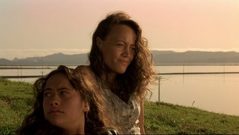 Movie still from “Once Were Warriors” (1994), directed by Lee Tamahori – A woman sitting next to another woman on a grassy hill; Close Up shot, Low angle
