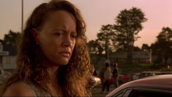 Movie still from “Once Were Warriors” (1994), directed by Lee Tamahori – A person with curly hair near a car; Close Up shot, Low angle