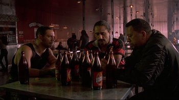 Movie still from “Once Were Warriors” (1994), directed by Lee Tamahori – A group of men sitting around a table with beer; Medium shot, Over the shoulder angle
