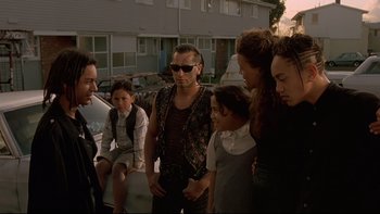 Movie still from “Once Were Warriors” (1994), directed by Lee Tamahori – A group of people standing next to each other on the street; Medium shot, Over the shoulder angle
