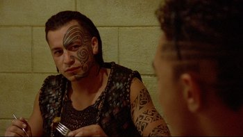 Movie still from “Once Were Warriors” (1994), directed by Lee Tamahori – A man with a tattoo on his face looking at himself in the mirror; Close Up shot, Over the shoulder angle
