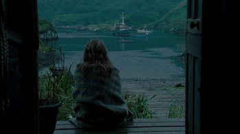 Movie still from “Ondine” (2009), directed by Neil Jordan – A woman sitting on a bench looking out at a body of water; Wide shot, High angle