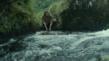 Movie still from “Ondine” (2009), directed by Neil Jordan – A man is jumping into a stream while holding his feet; Wide shot, High angle