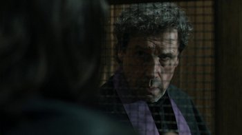 Movie still from “Ondine” (2009), directed by Neil Jordan – A man in a purple and black robe smoking a cigarette in front of a window; Close Up shot, Over the shoulder angle