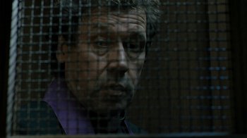 Movie still from “Ondine” (2009), directed by Neil Jordan – A man in a suit looking through a fence; Close Up shot, Low angle