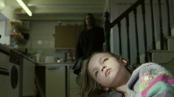 Movie still from “Ondine” (2009), directed by Neil Jordan – A young girl sitting on the stairs of a house; Medium shot, Over the shoulder angle