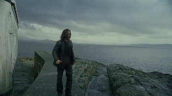 Movie still from “Ondine” (2009), directed by Neil Jordan – A man standing next to the ocean on a cloudy day; Wide shot, Low angle