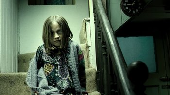 Movie still from “Ondine” (2009), directed by Neil Jordan – A young girl sitting on a chair in a room; Medium shot, Low angle