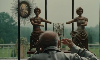 Movie still from “One Hundred and One Nights” (1995), directed by Agnès Varda – An older man sitting in front of a window; Medium shot, Over the shoulder angle