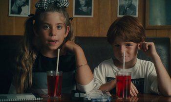 Movie still from “One Hundred and One Nights” (1995), directed by Agnès Varda – Two children sitting at a table with drinks; Close Up shot, High angle