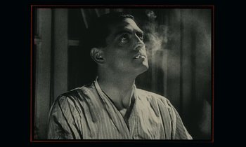 Movie still from “One Hundred and One Nights” (1995), directed by Agnès Varda – A man is smoking a cigarette and looking up; Close Up shot, Low angle
