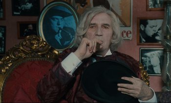 Movie still from “One Hundred and One Nights” (1995), directed by Agnès Varda – A man smoking a cigarette in front of a mirror; Medium shot, Over the shoulder angle