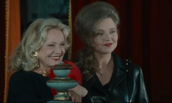 Movie still from “One Hundred and One Nights” (1995), directed by Agnès Varda – Two older women standing next to each other in a room; Medium shot, Over the shoulder angle