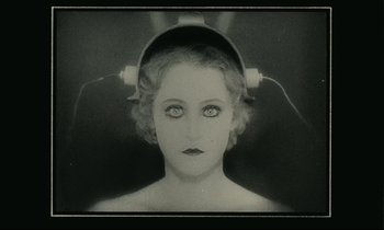 Movie still from “One Hundred and One Nights” (1995), directed by Agnès Varda – An old photo of a woman with headphones on her head; Close Up shot, High angle