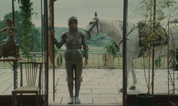Movie still from “One Hundred and One Nights” (1995), directed by Agnès Varda – A woman dressed as joan of arc standing in front of a white horse; Wide shot, Low angle