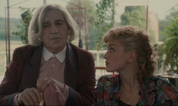 Movie still from “One Hundred and One Nights” (1995), directed by Agnès Varda – An older man and a young woman sitting next to each other; Medium shot, Over the shoulder angle