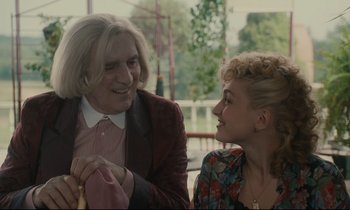 Movie still from “One Hundred and One Nights” (1995), directed by Agnès Varda – A man and a woman smiling at each other; Medium shot, Over the shoulder angle