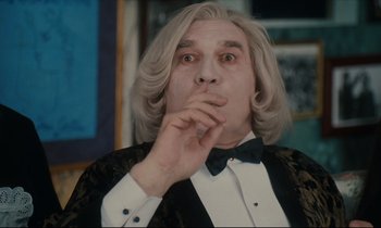 Movie still from “One Hundred and One Nights” (1995), directed by Agnès Varda – A man with long hair wearing a suit and bow tie; Medium shot, Low angle
