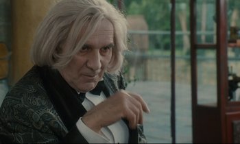 Movie still from “One Hundred and One Nights” (1995), directed by Agnès Varda – An old man with white hair and a black jacket; Close Up shot, Over the shoulder angle