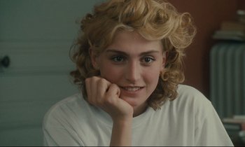 Movie still from “One Hundred and One Nights” (1995), directed by Agnès Varda – A person with curly blonde hair; Close Up shot, Over the shoulder angle