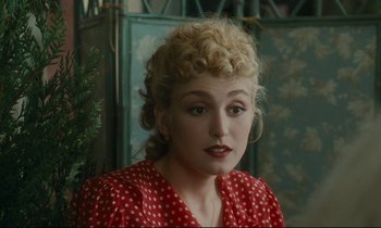 Movie still from “One Hundred and One Nights” (1995), directed by Agnès Varda – A woman in a red polka dot dress with blonde curly hair; Close Up shot, Over the shoulder angle