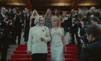 Movie still from “One Hundred and One Nights” (1995), directed by Agnès Varda – A man and a woman walking down the steps of a red carpet; Wide shot, Low angle