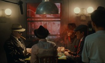 Movie still from “One Hundred and One Nights” (1995), directed by Agnès Varda – A group of men sitting around a table playing cards; Wide shot, High angle