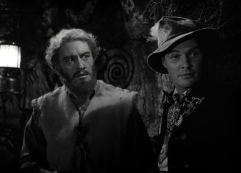 Movie still from “One Million B.C.” (1940), directed by Hal Roach Jr. – A man and a man with a beard and a hat; Medium shot, Over the shoulder angle