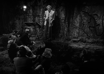 Movie still from “One Million B.C.” (1940), directed by Hal Roach Jr. – An old man standing in front of a group of people; Wide shot, High angle