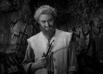 Movie still from “One Million B.C.” (1940), directed by Hal Roach Jr. – A man with a long beard holding a pair of scissors; Medium shot, Over the shoulder angle