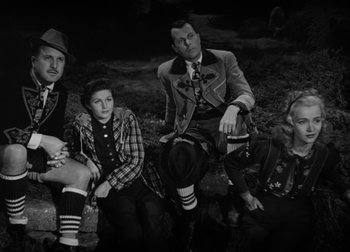 Movie still from “One Million B.C.” (1940), directed by Hal Roach Jr. – A black and white photo of a group of people sitting on the ground; Wide shot, High angle