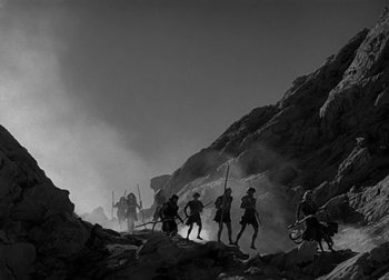 Movie still from “One Million B.C.” (1940), directed by Hal Roach Jr. – A black and white photo of a group of people walking up a mountain; Extreme Wide shot, Low angle