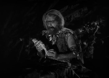 Movie still from “One Million B.C.” (1940), directed by Hal Roach Jr. – A man with long hair and a long beard holding a bird; Medium shot, High angle