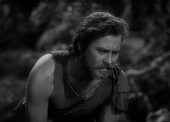 Movie still from “One Million B.C.” (1940), directed by Hal Roach Jr. – Black and white photograph of a man smoking a pipe; Close Up shot, Over the shoulder angle