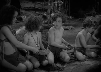 Movie still from “One Million B.C.” (1940), directed by Hal Roach Jr. – A black and white photo of a group of children sitting on the ground; Medium shot, High angle