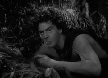 Movie still from “One Million B.C.” (1940), directed by Hal Roach Jr. – Black and white photograph of a man laying in the jungle; Medium shot, High angle