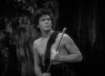 Movie still from “One Million B.C.” (1940), directed by Hal Roach Jr. – A man holding a stick in front of a tree; Medium shot, Low angle