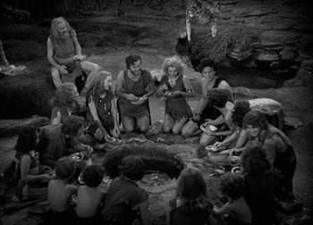 Movie still from “One Million B.C.” (1940), directed by Hal Roach Jr. – A black and white photo of a group of people sitting around a fire pit; Wide shot, High angle
