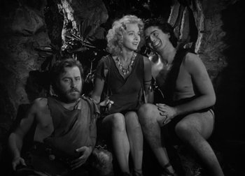 Movie still from “One Million B.C.” (1940), directed by Hal Roach Jr. – A group of people sitting next to each other in a cave; Medium shot, High angle